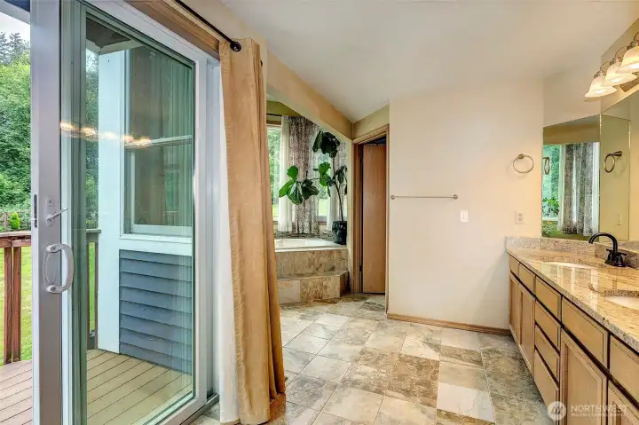 Five piece primary bathroom with tile flooring, newer granite counter top, double vanity and slider to the deck.