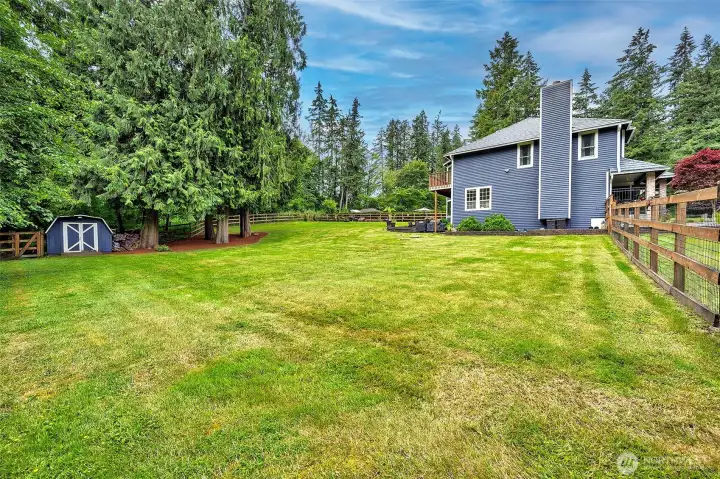 View to the west with a detached shed and a negotiable riding lawn mower. The fence has an large gate to the back yard for RV parking etc..