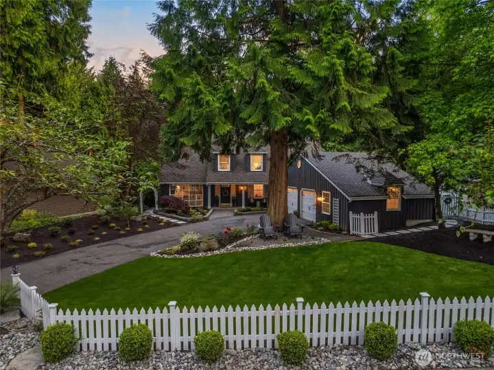 The front yard offers an impressive first impression, featuring a broad, manicured lawn, established landscaping, charming white picket fence, and the home’s classic façade, coming together to create a lush and inviting outdoor approach.