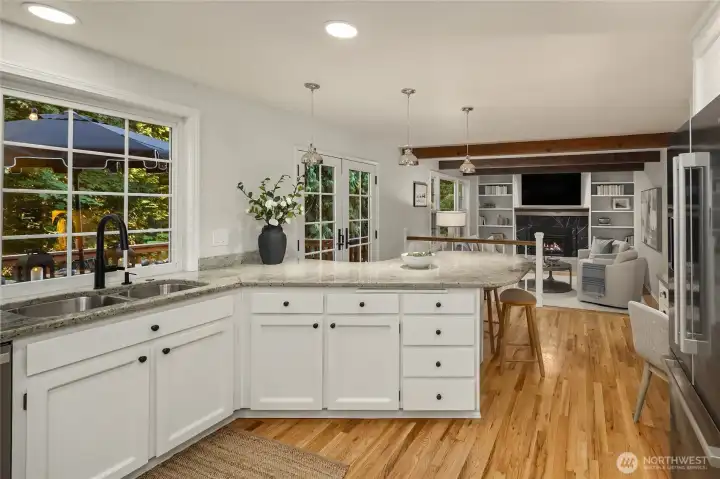This well-appointed kitchen features newly painted cabinetry, oil rubbed bronze hardware, Hudson Valley light fixtures, granite countertops, stainless steel appliances, and bar seating.