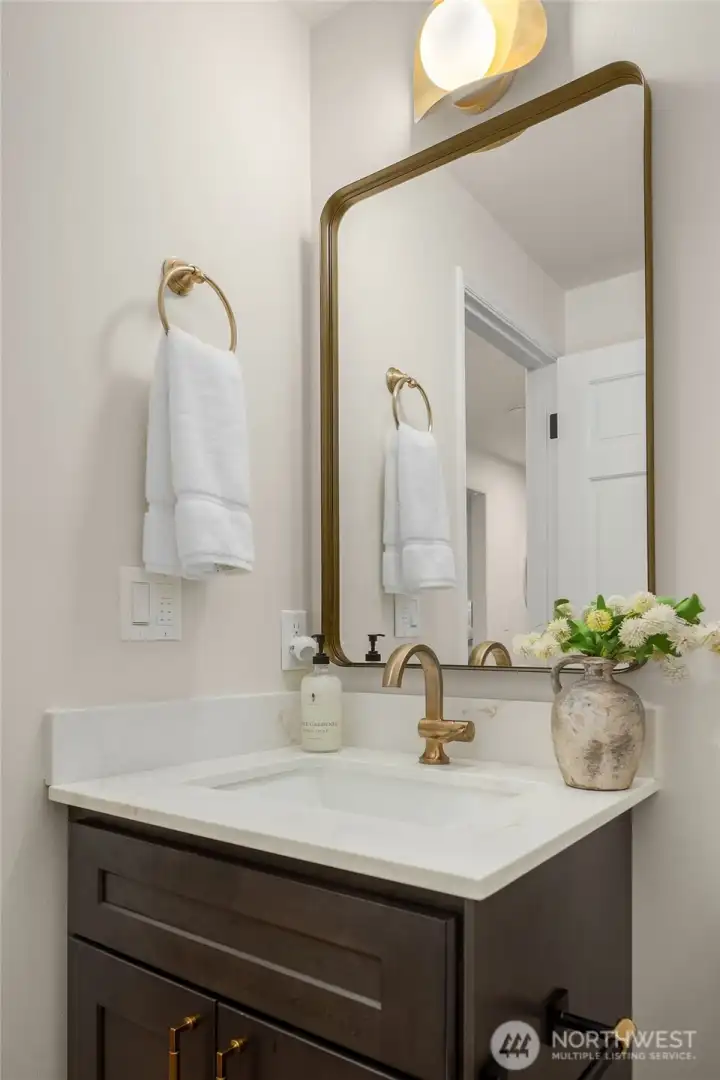 Jewel box powder room completely refinished - off the hallway from the bonus/family room. Brand new custom cabinetry, new mirror, burnished gold hardware and plumbing fixtures with brass designer lighting sourced from Europe by LightCove.