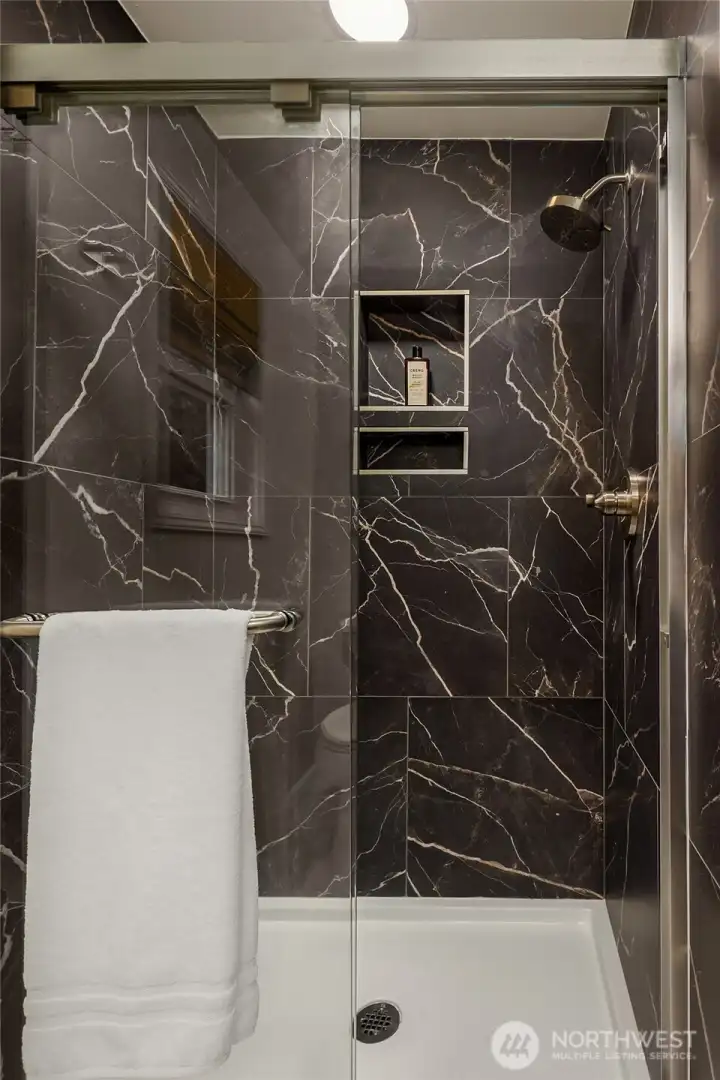 Gorgeous porcelain clad shower. Easy to maintain. Visual Comfort sconce above new Andy Star mirror, custom stained cabinetry and polished nickel hardware.