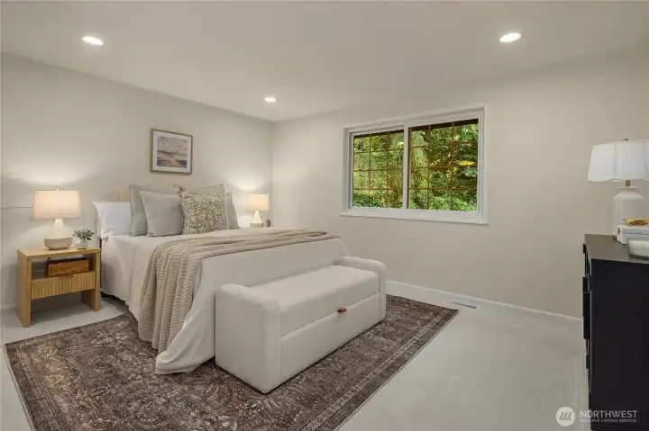This bright and inviting upper level bedroom offers a comfortable and versatile space, featuring new premium carpet, fresh neutral paint, and large windows that fill the room with warm natural light, privacy, and lovely views of the wooded greenbelt below.