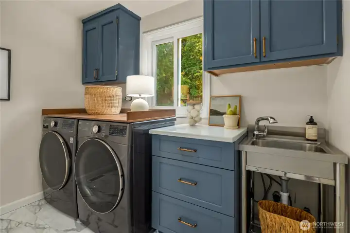 Conveniently positioned on the main level, this well-appointed laundry room delivers true everyday function with a full-size washer and dryer, abundant cabinetry, and a utility sink — keeping laundry day streamlined, organized, and blissfully under control. New porcelain LVP flooring makes clean up a breeze.