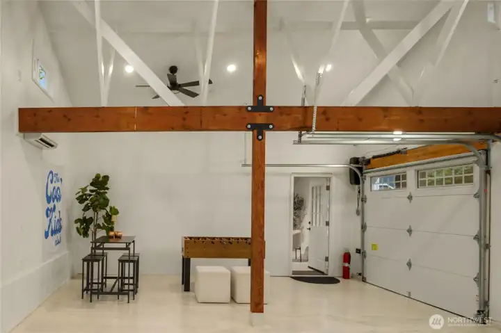 The pièce de résistance of garages: one of the home's other unique, stand out features, this garage has soaring ceilings, overhead fans, transom windows, white washed floors, rich beams, and a coveted mini split for controlled temperature. The sky is the limit - use it as a luxury garage or make it a wellness and workout zone. A true flex space. Adjacent to a huge executive office space.