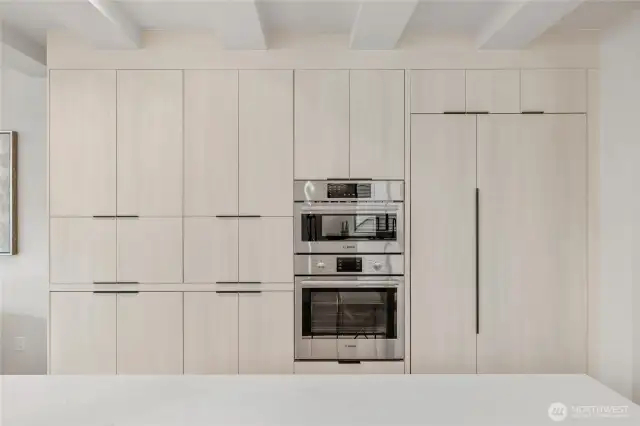 A wall of cabinets and a built-in refrigerator offer ample storage while maintaining a streamlined, modern look.