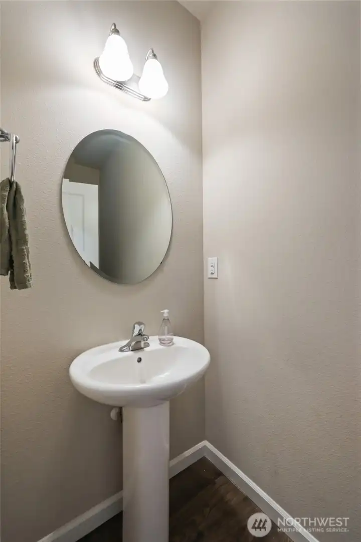 1/2 bath at entry with charming pedestal sink and round mirror for style.