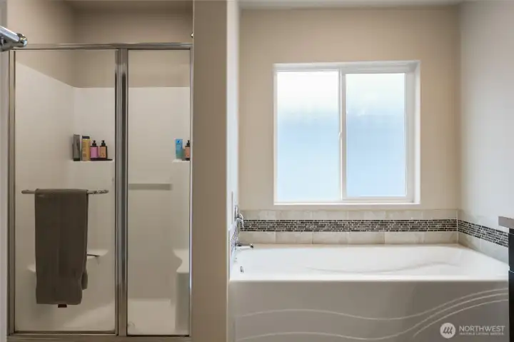 Frosted window over the deep soaking tub provides wonderful light without compromising privacy! Roomy shower with glass door offers shelves and seats for ideal convenience. Linen closet and private commode room left of photo.