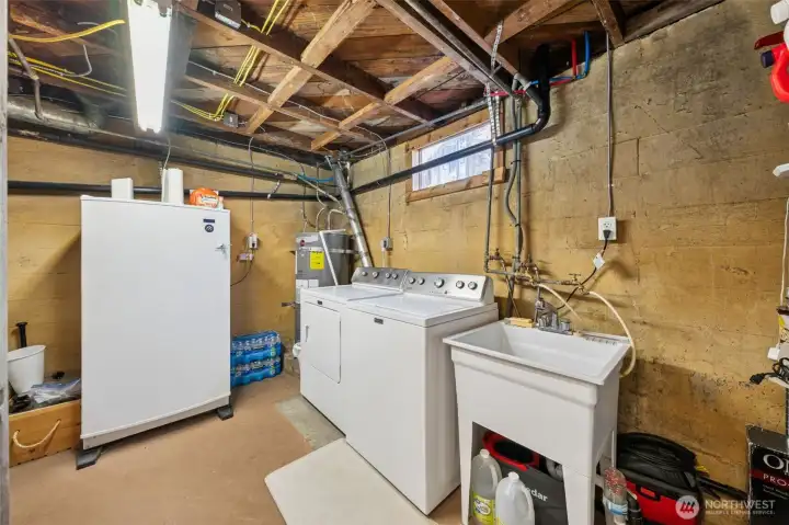 Unfinished part of the basement with laundry, deep sink & room for a freezer for extra storage needs.