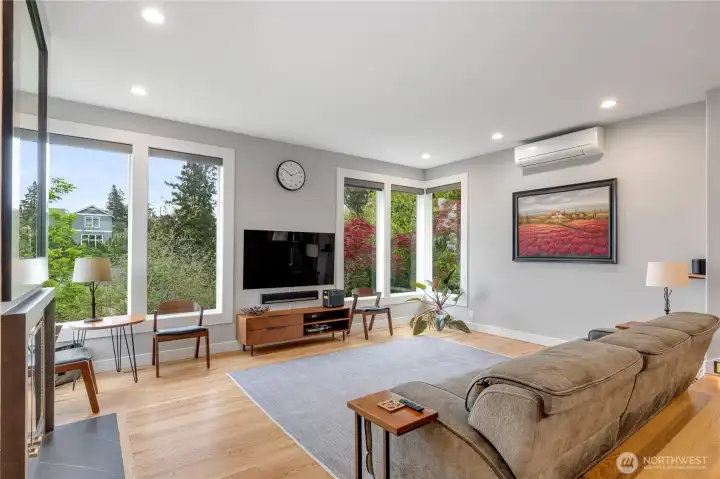 The sunken living room looks to the green space and out to the city and mountains. While there is a mini split in this room, there is a new HVAC system with central AC for comfort throughout the house in every season. The windws are fitted with app-controlled blinds for additional comfort.