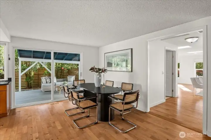 Dining Area – Casual dining space with hardwood flooring and direct access to the covered outdoor deck through sliding glass doors. Large windows provide backyard views and natural light.
