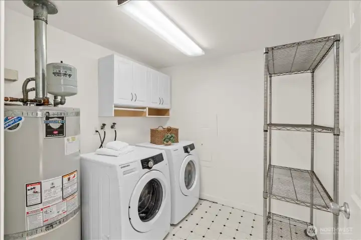 Laundry Room – Dedicated laundry room with side-by-side washer and dryer, overhead storage cabinets, and additional shelving. Functional layout offers convenient space for household organization.