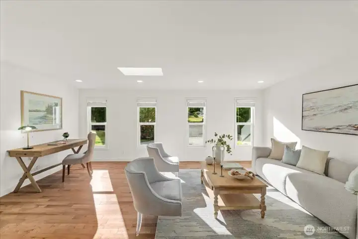 Living Room – Bright living area featuring hardwood flooring, recessed lighting, skylight, and multiple windows that fill the space with natural light. Flexible layout accommodates both seating and work-from-home needs.