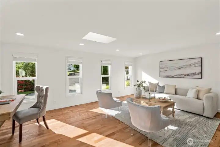 Living Room – Spacious living room with expansive windows, skylight, and hardwood floors. Open design creates a comfortable setting for everyday living and entertaining.