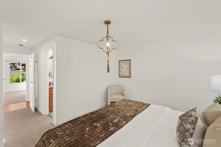 Primary Bedroom – Spacious bedroom with soft carpeting, neutral finishes, and an adjoining bath. Large window provides natural light and views of the surrounding landscape.