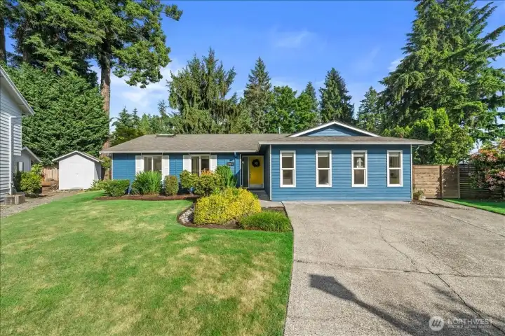Front Exterior – Welcoming curb appeal with established landscaping, expansive lawn area, and mature trees surrounding the property. Long driveway provides convenient off-street parking.