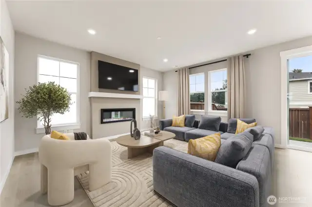 Open concept great room surrounded by windows and modern fireplace. Virtual staging in photo.