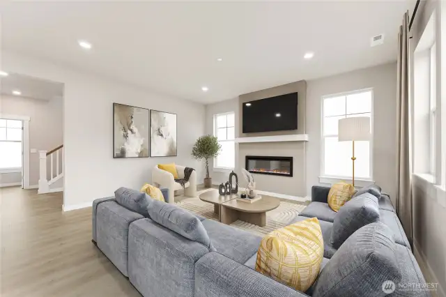 Open concept great room surrounded by windows and modern fireplace. Virtual staging in photo.