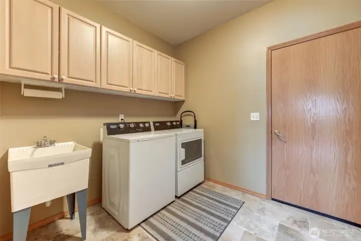 The laundry room has upper cabinetry and laundry sink.