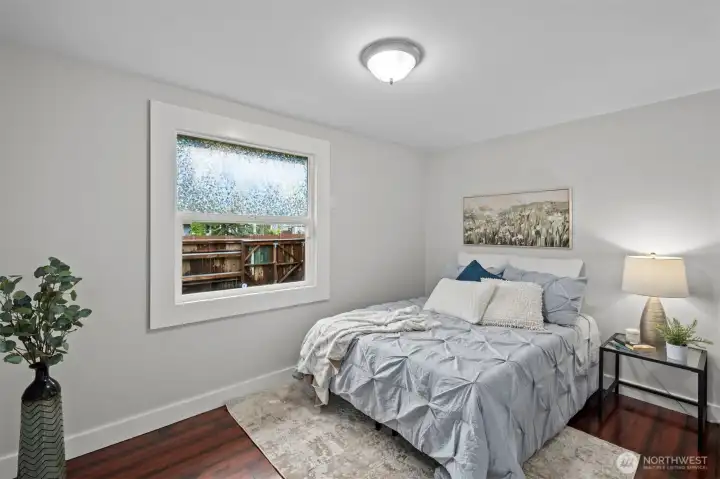 Bright primary bedroom features privacy glass on the window but still lets in natural light.