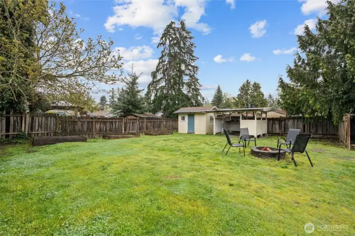 Large fully-fenced yard, garden boxes, storage shed, covered workbench and firepit!