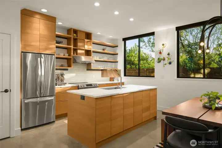 Custom kitchen features marble countertops, induction range, a walk-in pantry with appliance storage and sleek concrete floors.