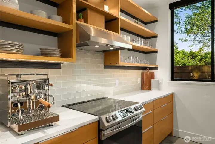 Custom kitchen features marble countertops, induction range, a walk-in pantry with appliance storage and sleek concrete floors.