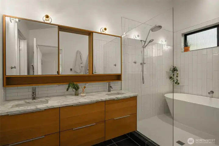 Primary ensuite features radiant heated floors, a water closet, freestanding tub, walk-in shower, and a luxurious double vanity sink with ample storage.