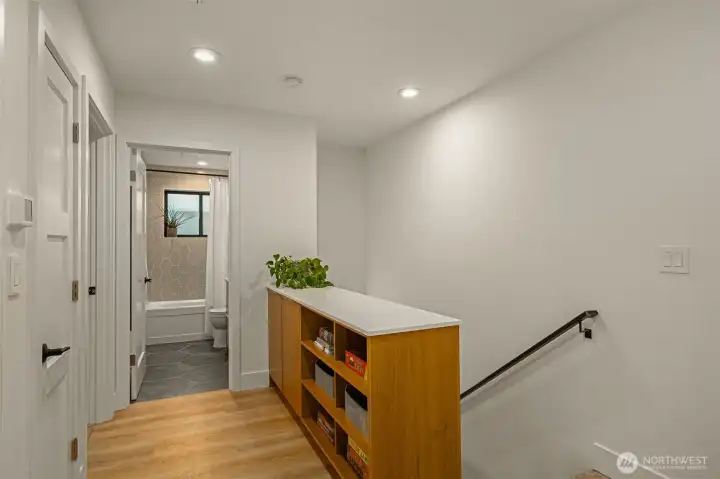 Upstairs landing features the laundry room, custom shelving, a linen closet and a spacious secondary bath.