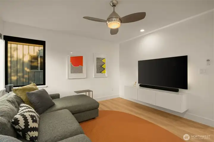 Secondary bedroom features custom shelving, a ceiling fan and engineered hardwood flooring.