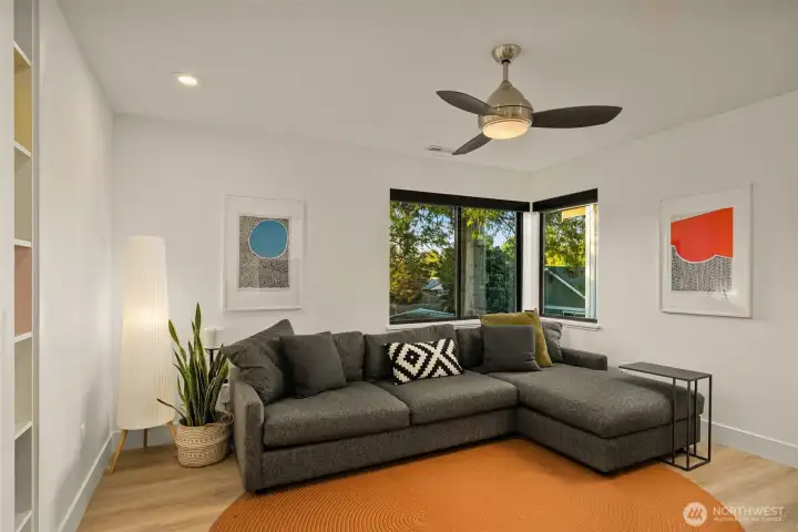 Secondary bedroom features custom shelving, a ceiling fan and engineered hardwood flooring.