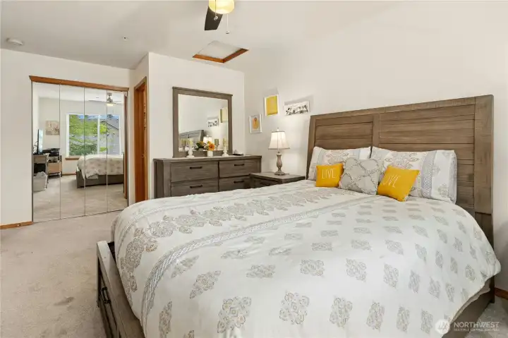 Elegant primary bedroom with mirrored walk-in and en suite bath