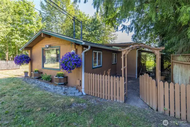 Shady back yard is enclosed by a charming picket fence with arbor