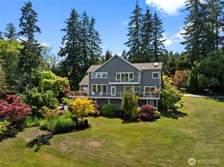 Rear elevation highlights the home's landscaped grounds, expansive lawn, and retreat-like setting. Rear elevation highlights the home's landscaped grounds, expansive lawn, and retreat-like setting.