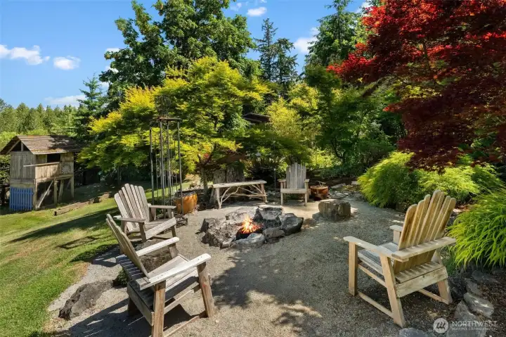 Thoughtfully designed outdoor living area features a fire pit and seating nestled among established gardens. Thoughtfully designed outdoor living area features a fire pit and seating nestled among established gardens.