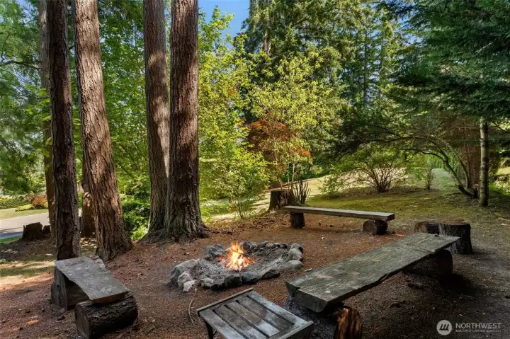 Outdoor gathering space includes a fire pit and handcrafted bench seating within a park-like setting. Outdoor gathering space includes a fire pit and handcrafted bench seating within a park-like setting.