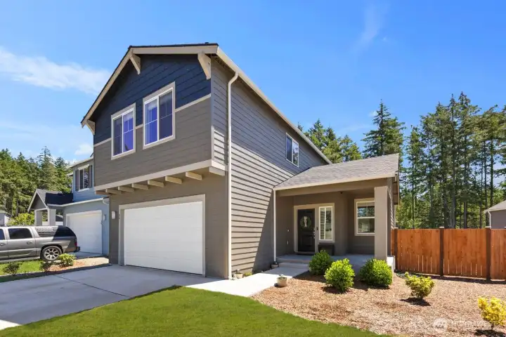 Angled view of the home's exterior highlighting the covered porch, driveway, and landscaped yard.