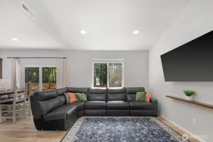 Living area with large windows, recessed lighting, and an open connection to the adjacent dining space.