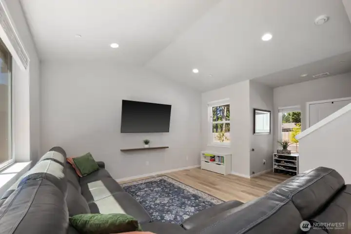 Living area with vaulted ceilings, recessed lighting, and multiple windows bringing in natural light.