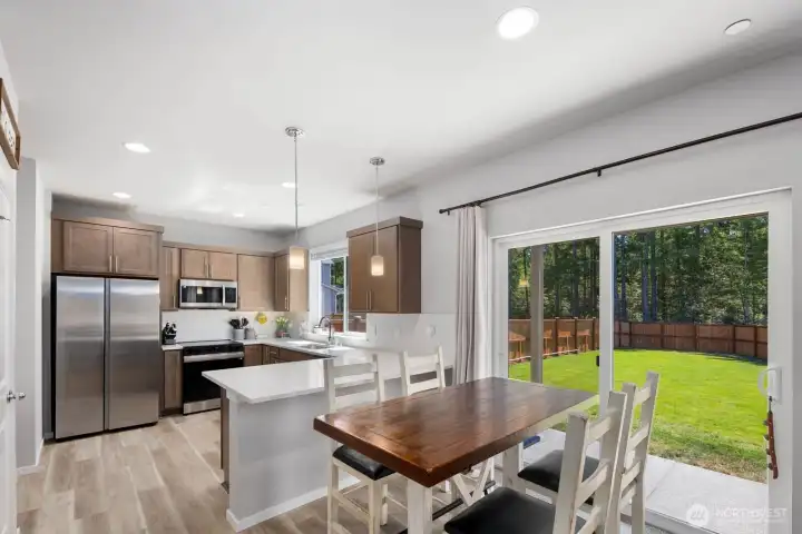 Kitchen and dining area with an open layout, center island, and sliding glass door providing access to the backyard.