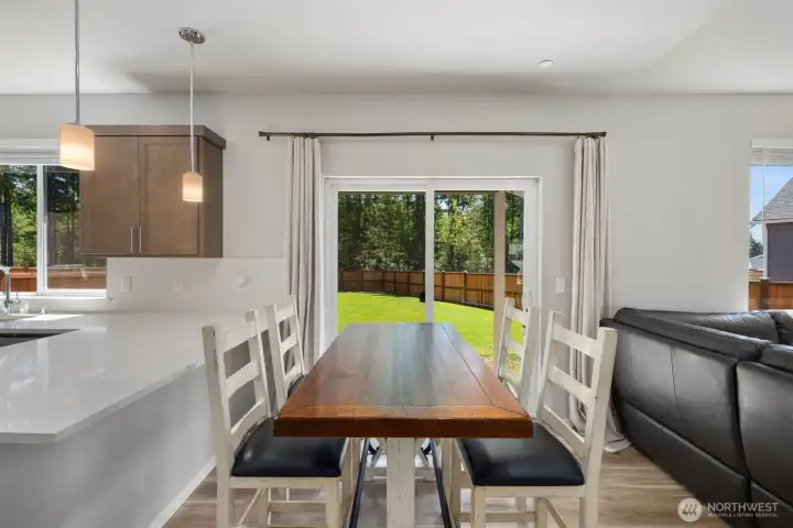 Dining area positioned adjacent to the kitchen with backyard views and direct access to the outdoor living space.