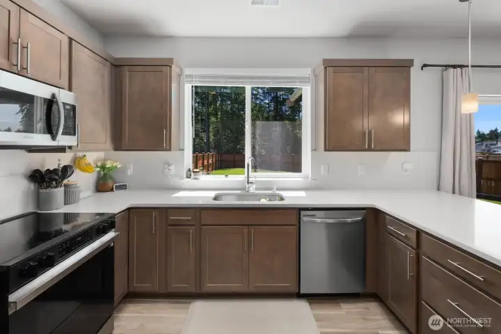 Kitchen with abundant workspace, stainless steel appliances, and a window bringing natural light into the room.