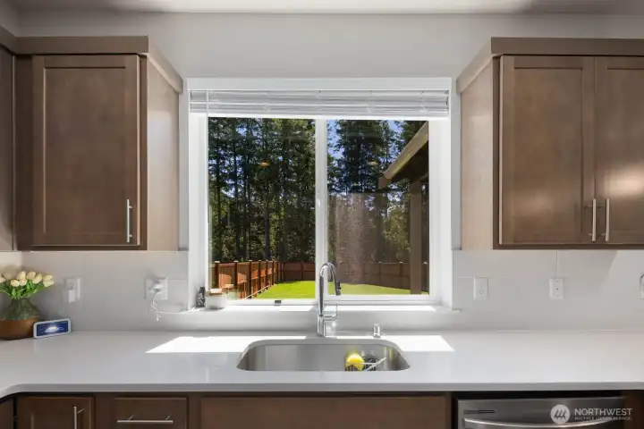 View from the kitchen sink overlooking the backyard and surrounding greenery.