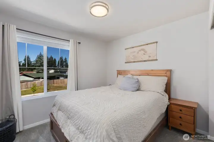 Bedroom with carpet flooring, natural light, and views through a large window.