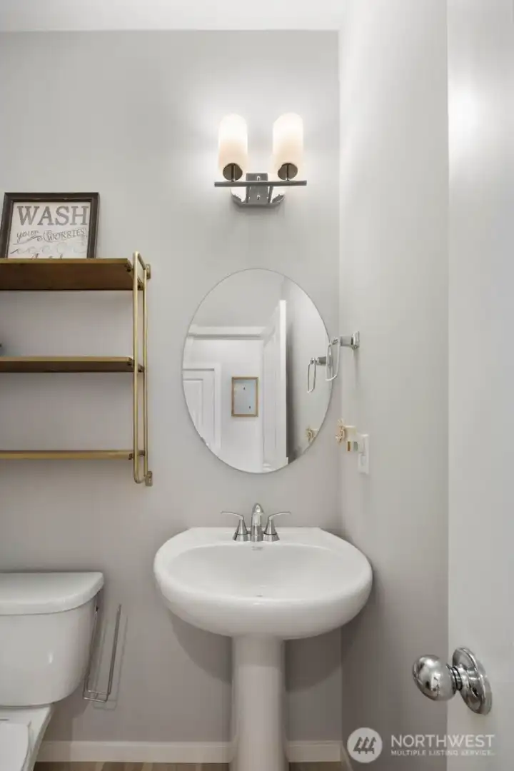 Powder room featuring a pedestal sink, mirror, and built-in shelving.