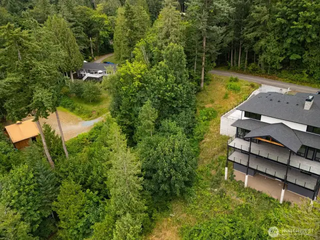 The wooded area between the two homes is this subject property.