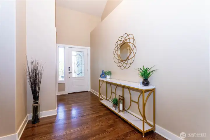 Step inside to a bright and open entryway with high ceilings, fresh paint, and rich hardwood floors. This foyer sets the tone for the entire home—spacious, elegant, and thoughtfully designed. Natural light pours through the glass door, highlighting the clean lines and warm color palette. It’s the kind of entrance that feels both inviting and impressive.