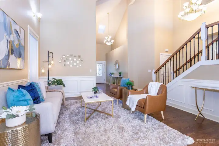 From this angle, you can appreciate the scale and design of the living room—airy, bright, and timeless. The two-story ceiling, elegant chandelier, and natural textures combine to create a space that feels both grand and inviting. Perfect for hosting friends or curling up by the window with a book.
