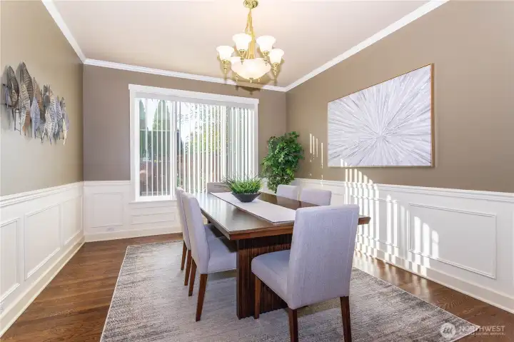 The formal dining room is a showpiece, featuring elegant wall molding, large picture windows, and a chandelier that adds warmth and charm. Whether it’s holiday dinners or everyday meals, this space feels both refined and comfortable. The light pours in during the day, creating a bright, welcoming atmosphere that anchors the heart of the home.