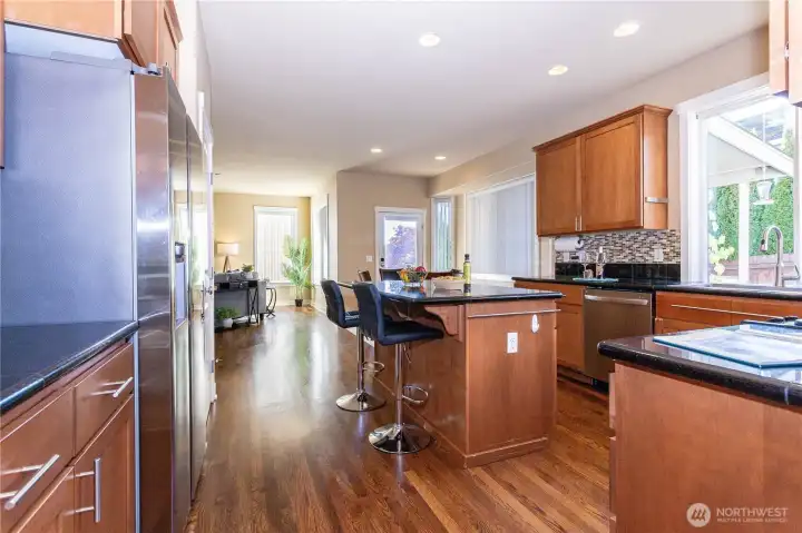 Spacious kitchen connects seamlessly to the family room, ideal for gathering. Hardwood floors, granite counters, and large picture windows create a bright, open feel leading to the backyard.